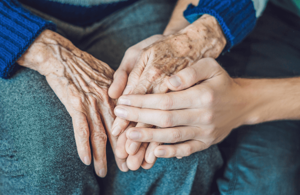 Hands of a young person and elderly person clasped together