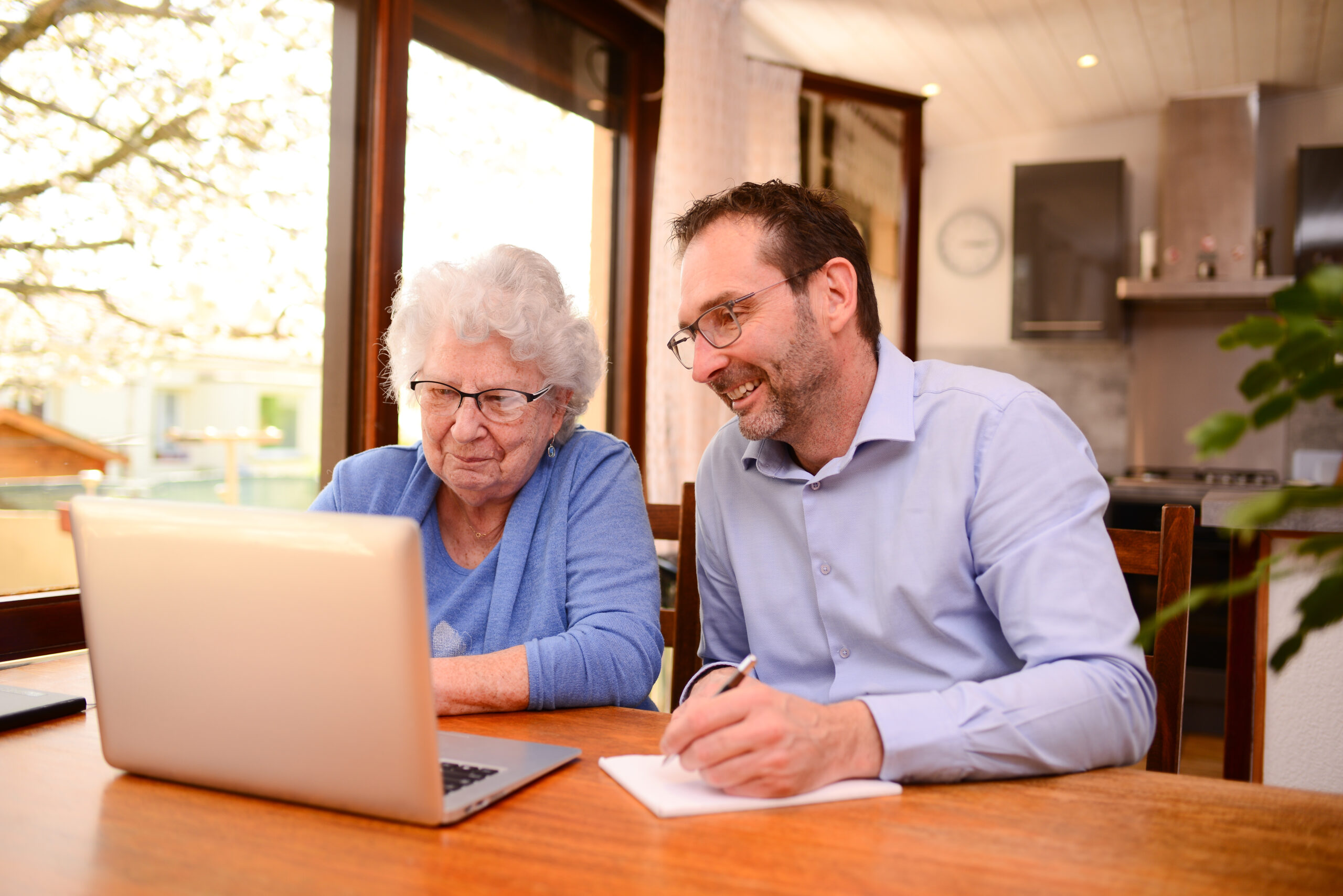 Woman and her advocate smiling while taking notes in front of a laptop